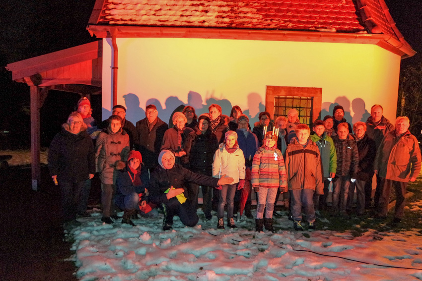 Die Teilnehmer des lebendigen Adventskalenders vor der weihnachtlich angestrahlten Kapelle an der Jägerbergstraße.